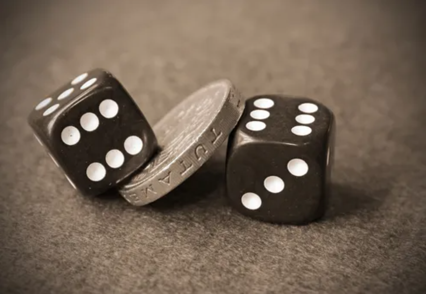 Dois dados pretos e uma moeda simbolizando o acaso e os fundamentos da teoria das probabilidades